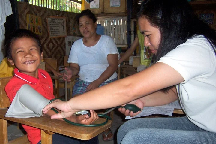 HELPS - A child smiles while his blood pressure is taken by a nurse, as part of our health program.